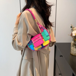 Colorful patchwork crescent underarm bag with gold buckle shown on a model in a modern room