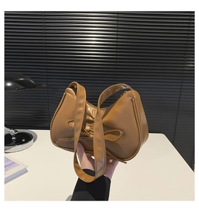 Detailed view of caramel brown bow handbag with textured faux leather and rounded shape