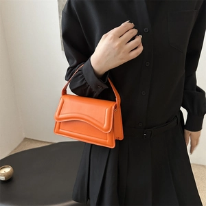 Trendy bright orange square underarm bag with a unique wavy flap and high-quality leather texture