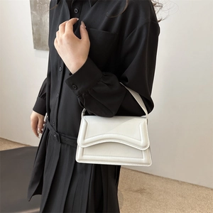 Chic white faux leather underarm bag with wavy stitching worn by a model in black