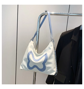 Detail of blue bow collage on white PU leather tote bag with silver chain strap