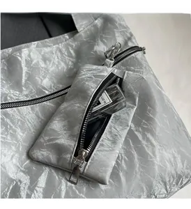 Detail of silver metallic tote bag featuring a detachable mini pouch and wrinkled texture