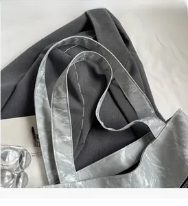 Detailed close-up of light gray pleated tote bag with metallic sheen and sturdy handles