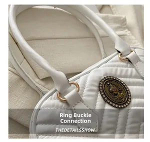 Close-up of white quilted leather bag with gold hardware and vintage crest emblem