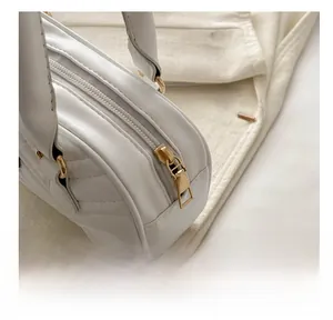 Detail shot of white quilted handbag showing smooth gold zipper and refined stitching