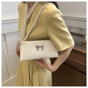 Detail of cream shoulder bag with bow buckle and textured ruched fabric
