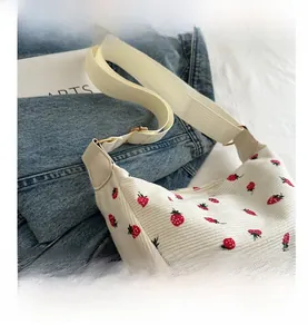 Detailed close-up of white corduroy crescent bag featuring red strawberry floral patterns