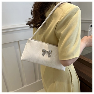 Détail du sac sous le bras en jacquard blanc avec noeud métallique argenté et fine bandoulière