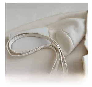 Detail of white PU leather bucket bag featuring narrow dual straps and silver rivets