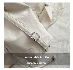 Macro detail of the silver adjustable buckle on a white glossy crossbody bucket bag