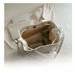 Spacious interior of white leather bucket bag showing umbrella, wallet and notepad