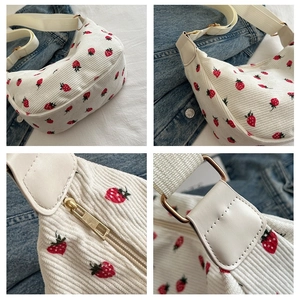 Detail of white corduroy crossbody bag with red strawberry print and golden metal zipper
