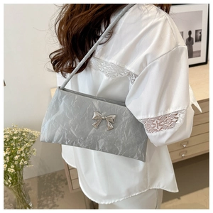 Détail de la texture plissée grise et du nœud argenté sur ce sac à bandoulière mode