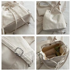 Detail view of cream drawstring bucket bag showing base, interior capacity and silver hardware