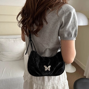 Sac hobo croissant noir minimaliste avec texture plissée et détail papillon argenté