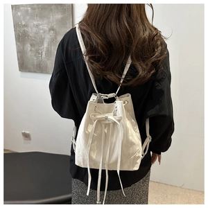 White drawstring bucket backpack shown on model with smooth texture and sleek finish