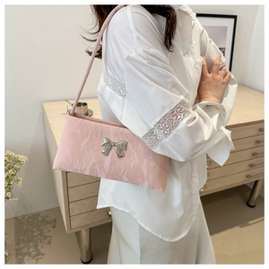 Gros plan sur un sac à bandoulière rose plissé avec nœud argenté et texture douce