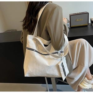 Detail of white wrinkled texture tote bag with metal zipper and mini pouch in lifestyle setting