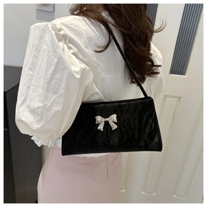 Vue détaillée d'un sac à bandoulière noir avec nœud papillon et texture brillante