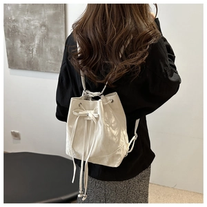 Detail of cream white drawstring bucket bag with bow decoration on model's back