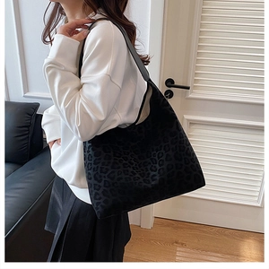 Close-up of black leopard print hobo bag with wide strap in a minimalist setting