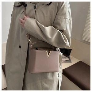 Detail of clay-colored pebbled leather handbag with gold V-shape metal hardware