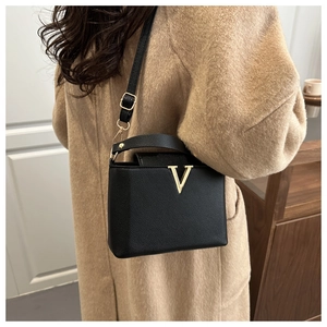 Détail du sac à main en cuir grainé noir avec logo V doré et bandoulière réglable