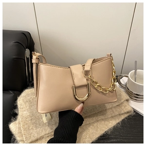 Détail du sac beige avec boucle en D dorée et décoration de chaîne épaisse