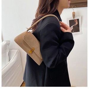 Dettaglio della borsa sottobraccio beige vintage con fibbia in oro opaco indossata da modella