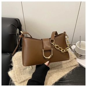 Détail du sac en similicuir marron avec boucle en D dorée et chaîne décorative épaisse