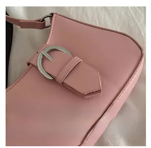 Detail of pink leather shoulder bag with a polished silver horseshoe metal buckle