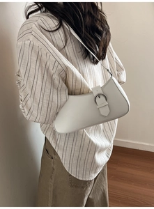 White crescent baguette bag featuring silver buckle detail and smooth leather finish