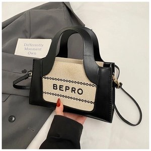 Detail of a bicolored crossbody bag featuring black leather and beige canvas texture with logo