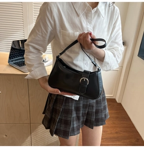 Detail der schwarzen Hobo-Tasche aus Kunstleder, gehalten von Model im Büro-Ambiente