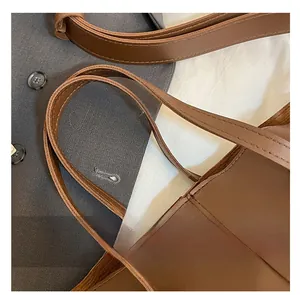 Detailed macro view of dark brown leather tote bag shoulder straps with neat stitching
