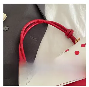 Detail of cherry print flap bag with red twisted handle and gold-tone hardware