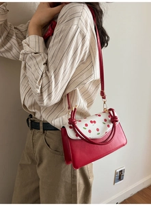 Détail d'un sac bandoulière rouge et blanc avec motif cerise et poignée nouée