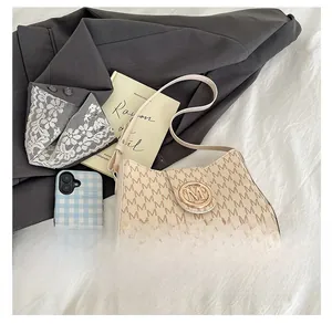Close-up of retro shoulder bag with M-pattern print and a large gold metal buckle