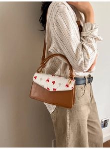 Détail d'un sac à main marron avec imprimé ours et cœur porté par un mannequin