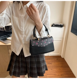 Fashionable black shoulder bag featuring pink floral print and elegant cylindrical handle