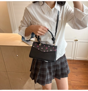 Détail du sac à main en PU noir avec nœud rose, motifs floraux et bandoulière réglable