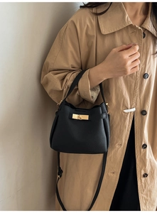 Détail du sac seau en cuir grainé noir avec fermoir doré tournant et bandoulière réglable