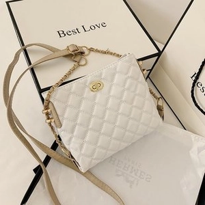 Detail of white quilted leather crossbody bag with gold buckle and metal chain strap