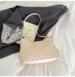 Detailansicht der cremefarbenen Baguette-Tasche mit M-Monogramm auf weißem Stoff