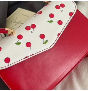 Détail de l'imprimé cerises sur sac en cuir bicolore avec fermoir en métal doré