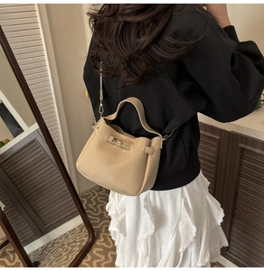 Vue détaillée d'un sac à main beige à motif litchi porté par une femme à l'arrière