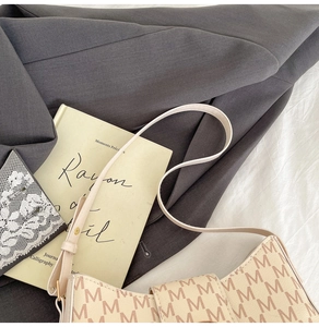 Détail du sac beige avec imprimé lettres marron posé sur une veste de costume grise chic