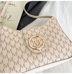 Gros plan sur le motif monogramme M et la boucle dorée logo de ce sac bandoulière chic