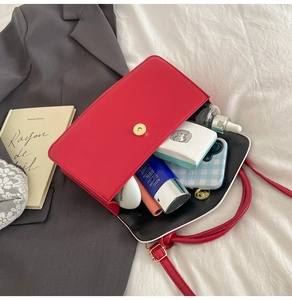 Détail du sac bandoulière en cuir rouge avec boucle dorée et intérieur spacieux