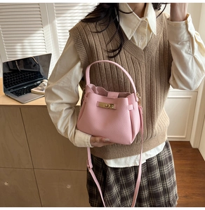Détail d'un sac seau rose texture litchi avec fermoir rotatif doré en scène réelle